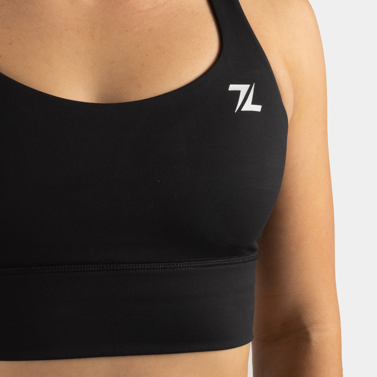 Detail van het logo aan de voorkant van de ZEUZ Sportbeha zwart